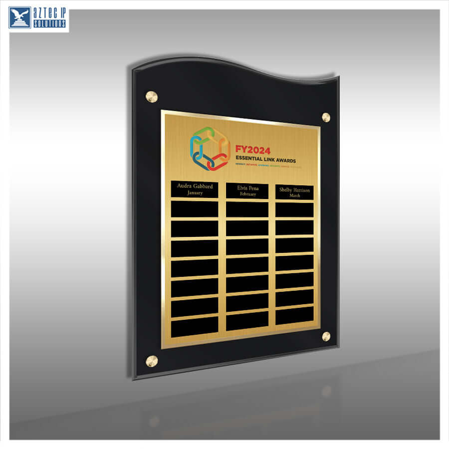 A black acrylic award plaque with a gold-plated face, featuring the text 'FY2024 ESSENTIAL LINE AWARD' and multiple name slots, shown on a gray gradient background.