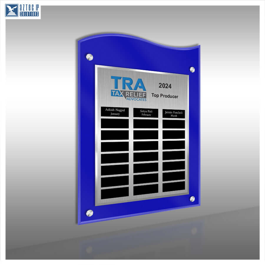 A blue acrylic wall plaque with a silver metal center panel, mounted on a gray gradient background. The plaque features the text 'TRA TAX RELIEF AWARD 2024 Top Producer' and three black nameplates at the bottom.
