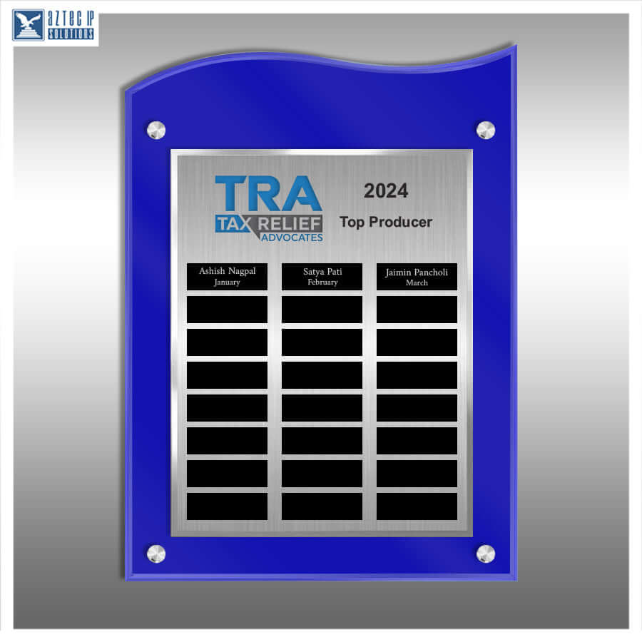 A blue-framed acrylic wall plaque with a brushed silver center panel, mounted on a gray gradient background. The plaque features the text 'TRA TAX RELIEF VIOVOCATE 2024 Top Producer' and three black name slots at the bottom.