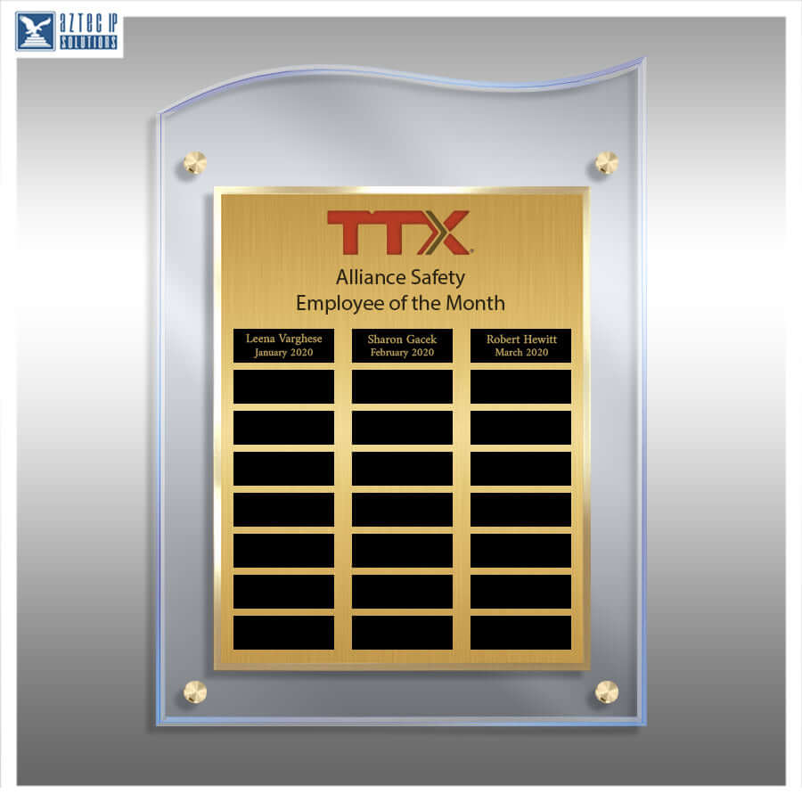 A vertical acrylic and brushed brass employee of the month plaque with the TTX logo, shown on a gray gradient background. The plaque features a gold-toned central panel with black nameplates and a clear arched acrylic frame with gold corner mounts.