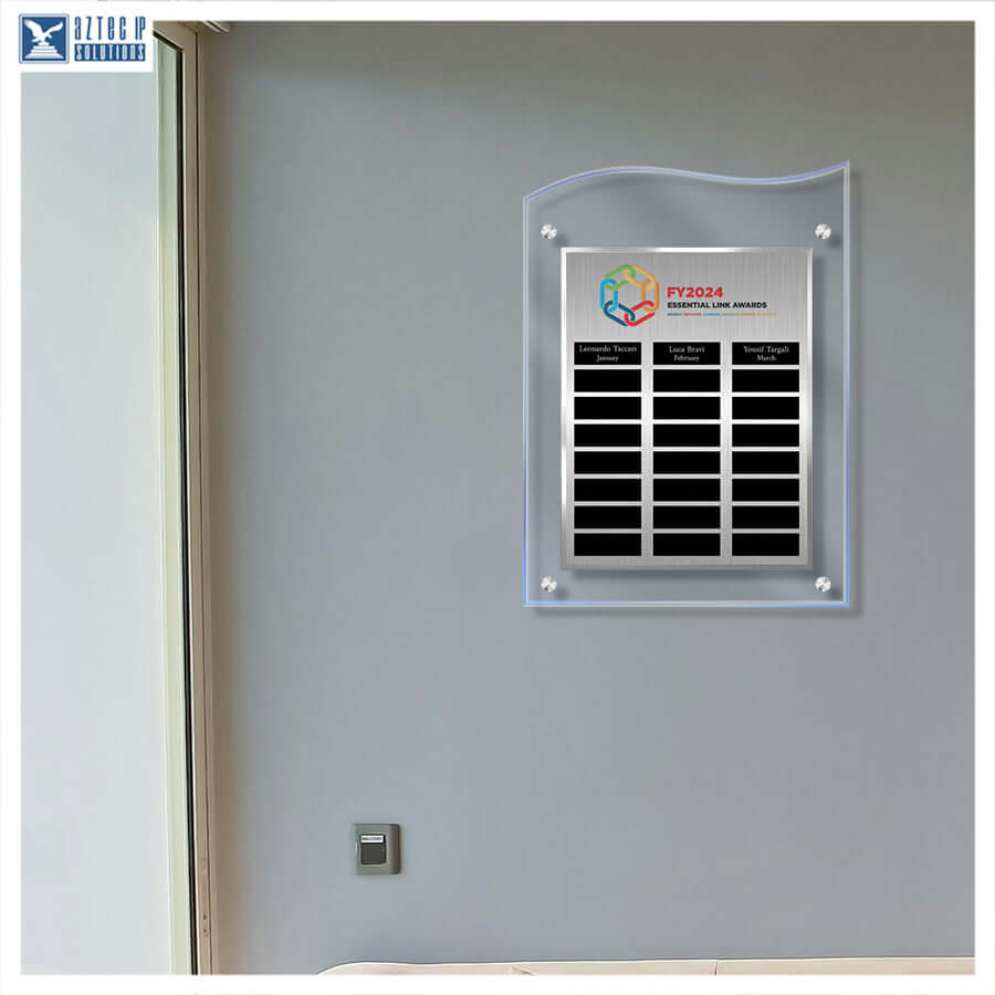 A wall-mounted acrylic and stainless steel solar nameplate display with three black nameplates, shown installed on a gray wall in an indoor setting.