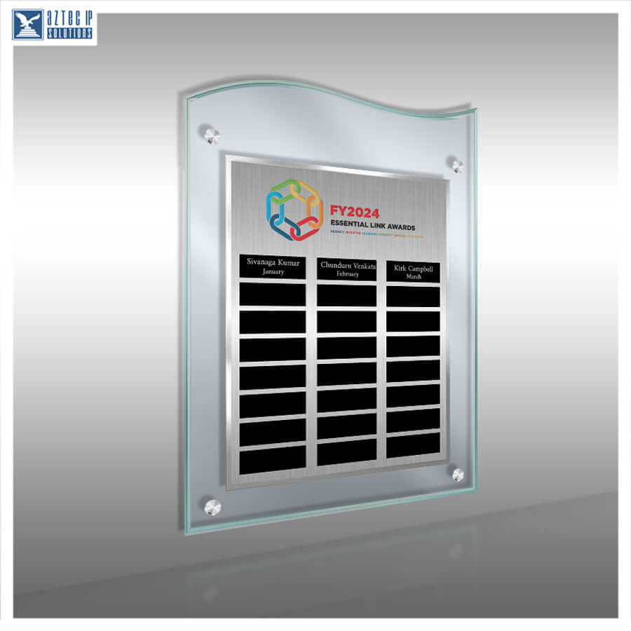 A clear acrylic wall plaque with a curved top and a silver metallic center panel, mounted on a light gray wall. The plaque features a printed FY2024 Essential Law Awards logo and multiple black nameplates for customization.
