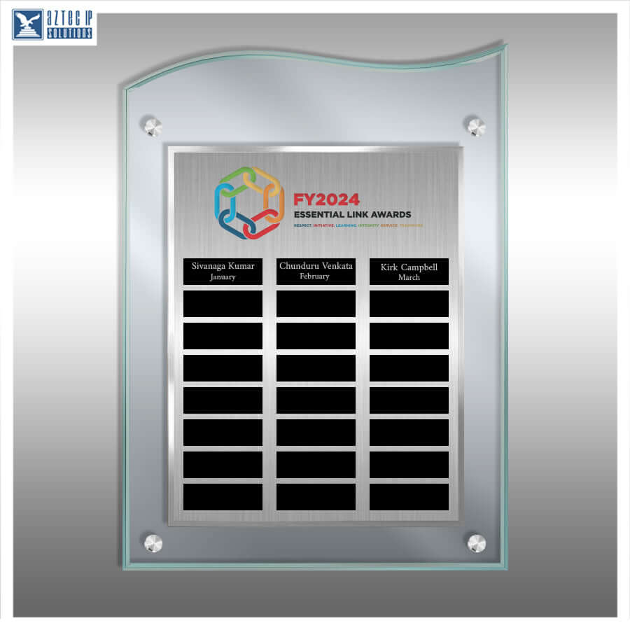 A custom acrylic and metal award plaque mounted on a gray wall. The plaque features a brushed silver center panel with the 'FY2024 Essential Link Awards' logo and three black nameplates at the bottom.