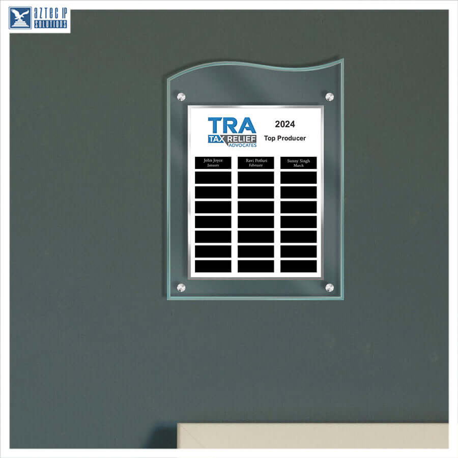 A custom acrylic wall plaque with a built-in solar panel array, mounted on a dark gray wall. The plaque features a white insert printed with the text 'TRA TAX RELIEF ASSOCIATE 2024 Top Producer' and several black name slots below.