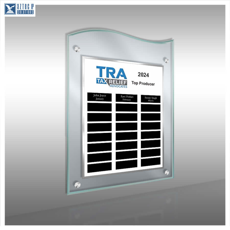 A clear acrylic wall plaque with a wavy top edge, mounted on a gray wall. The plaque contains a white insert with the blue and black text 'TRA TAX RELIEF ASSOCIATES 2024 Top Producer' and three black name slots.